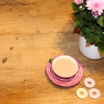 Wooden table with pink plant, tea and biscuits.